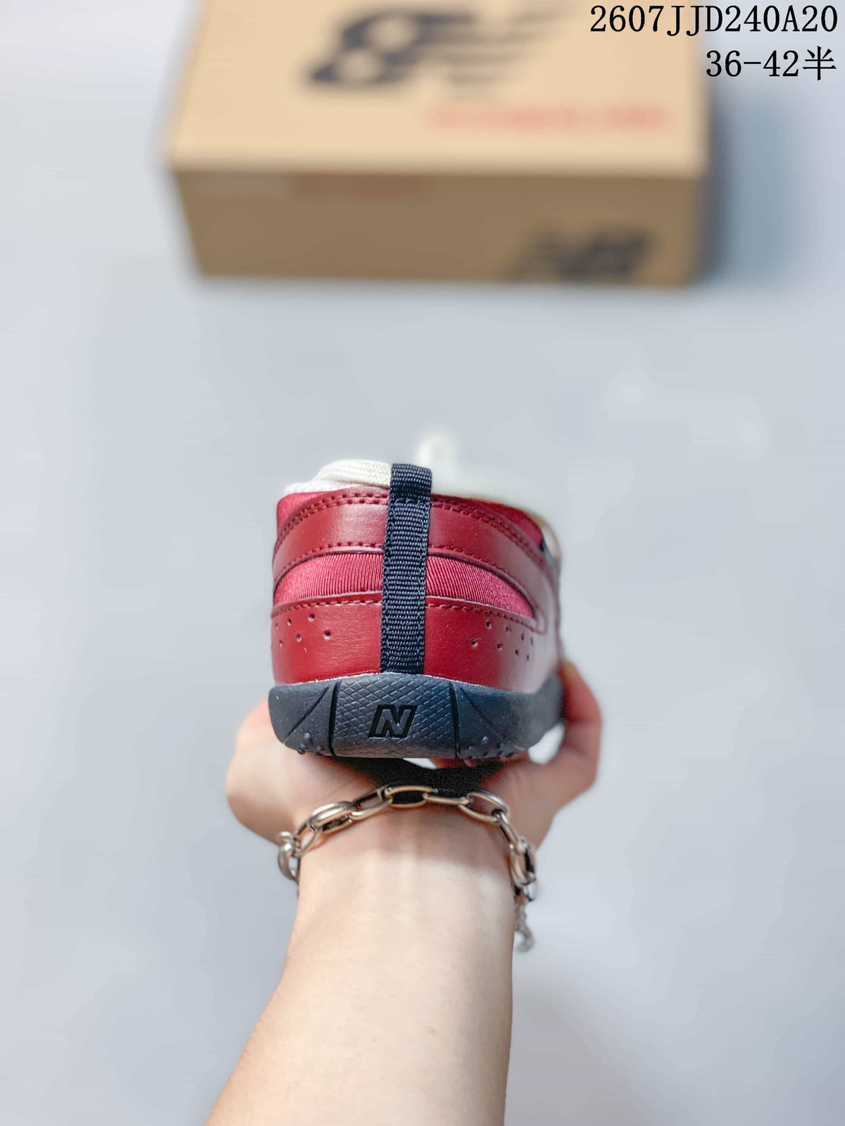 Rear view of the red sneaker showing layered heel panels, a dark vertical pull tab, and a dark outsole with an N mark.