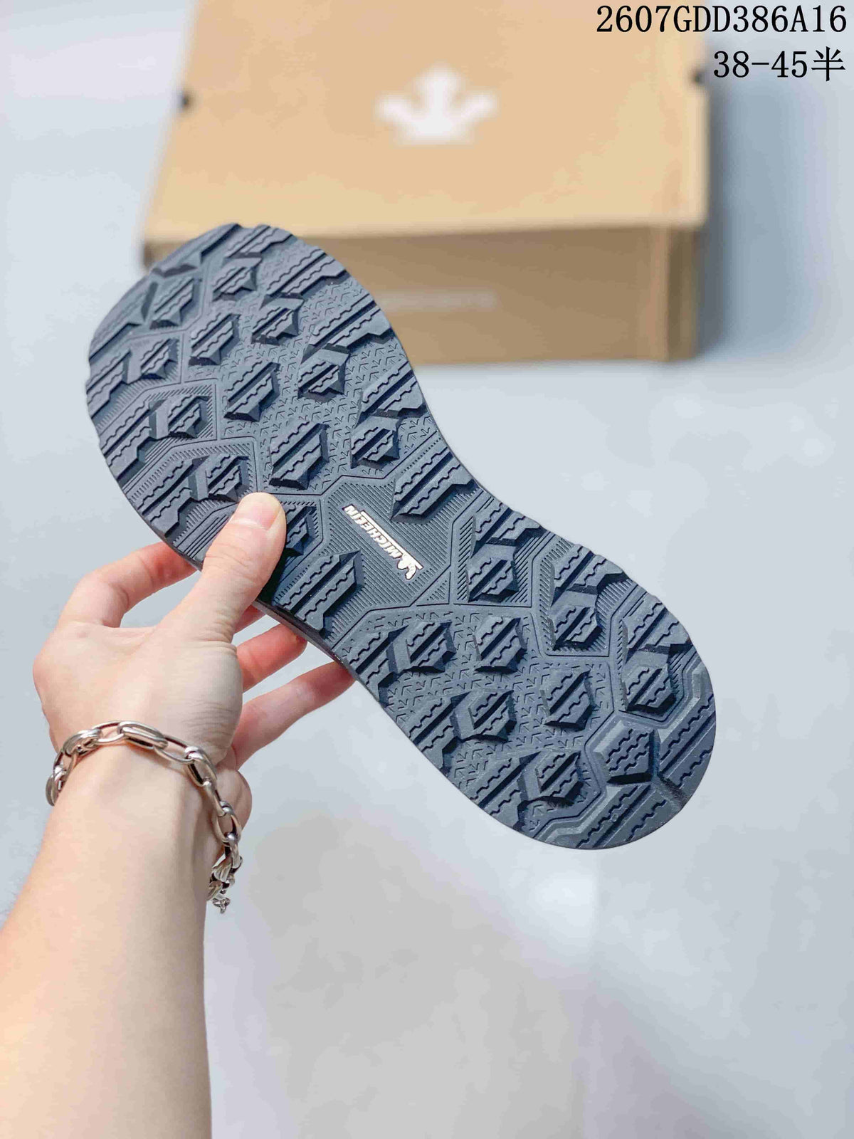 Underside view of the black sneaker showing the raised geometric outsole tread and central branding.
