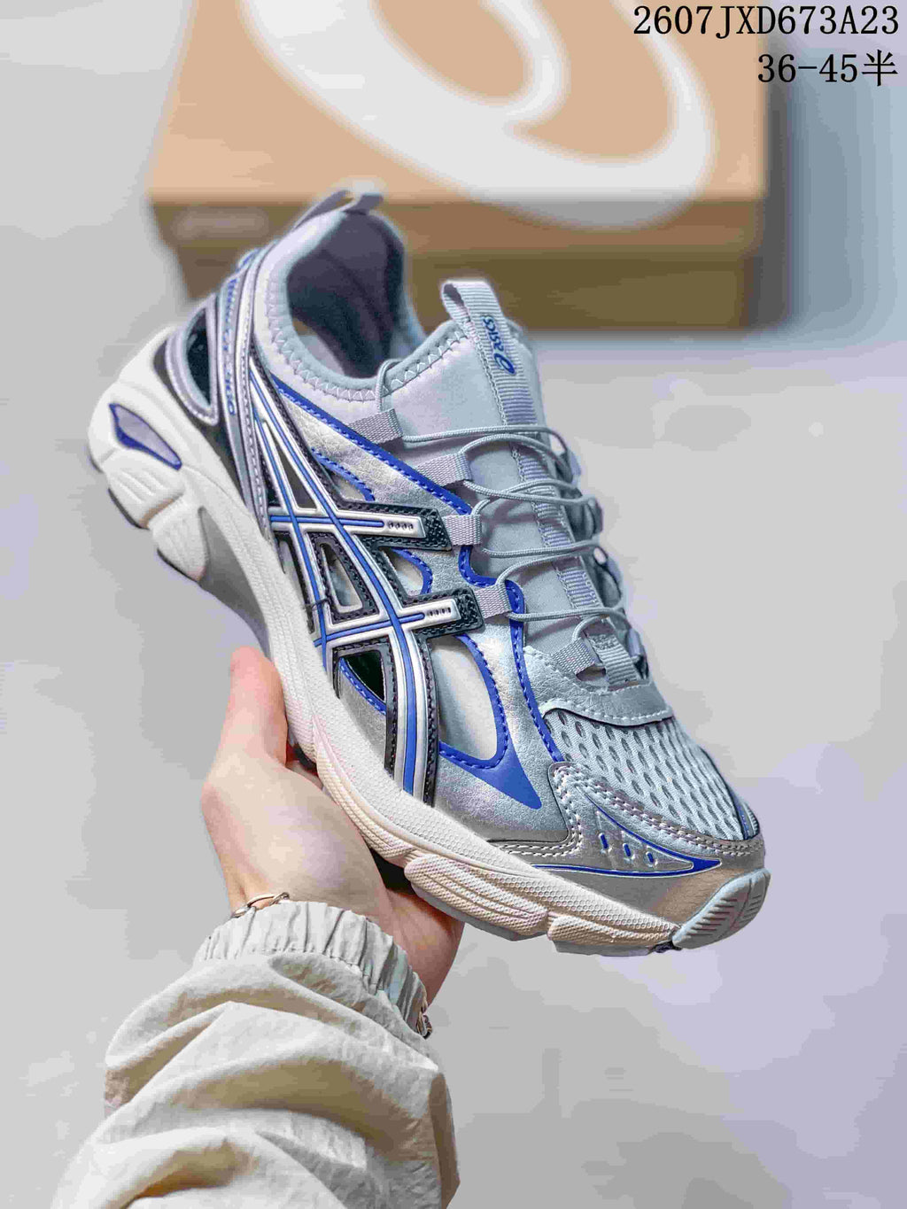 Angled side view of the silver and blue ASICS Gel-Kayano 14 sneaker showing its layered upper and sculpted sole.