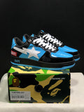 Black, blue, and white BAPE STA sneakers displayed on a camouflage BAPE shoe box; the box label shows a sample size of US 8, UK 7, EU 41, and CM 26.