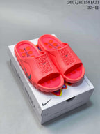 Pair of coral Nike Mind 001 mule slides displayed on a Nike Mind presentation box.