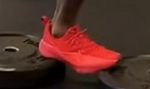 Side view of a red lace-up running-style sneaker being worn