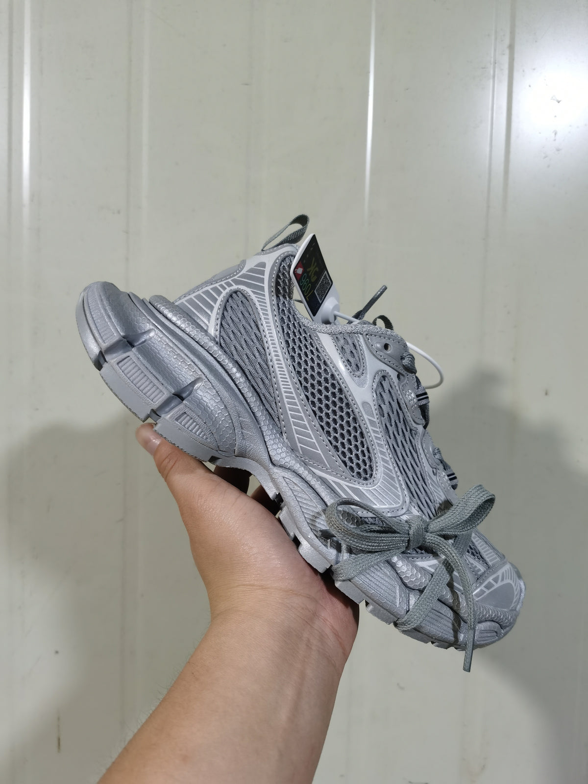 Angled front view of the grey mesh sneaker showing the lace area, layered upper panels and thick segmented outsole.