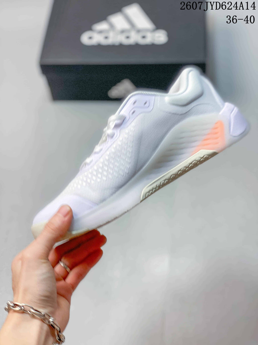 Side view of the white low-top training shoe showing the mesh-textured upper, side stripes, lace system, and outsole accents.
