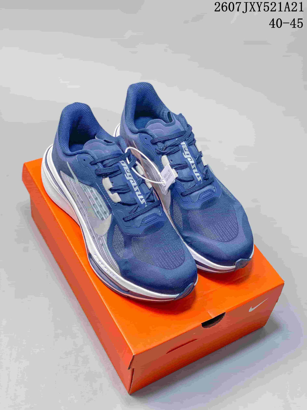 Pair of navy and white Nike sneakers displayed on an orange shoebox; overlay text shows 2607JXY521A21 and sizes 40–45.