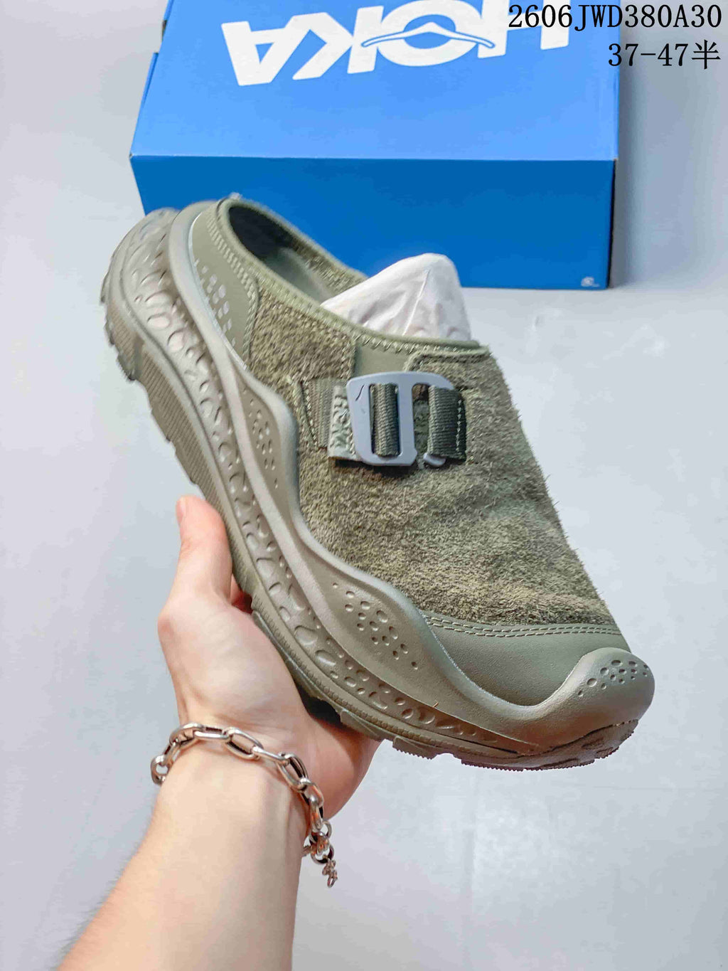 Angled view of the olive-toned mule sneaker with buckle detail and sculpted sole