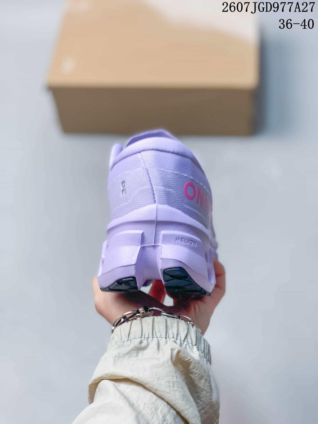 Rear view of a lavender sneaker showing padded collar, heel branding, segmented outsole, and the product text 2607JGD977A27 with size range 36–40.