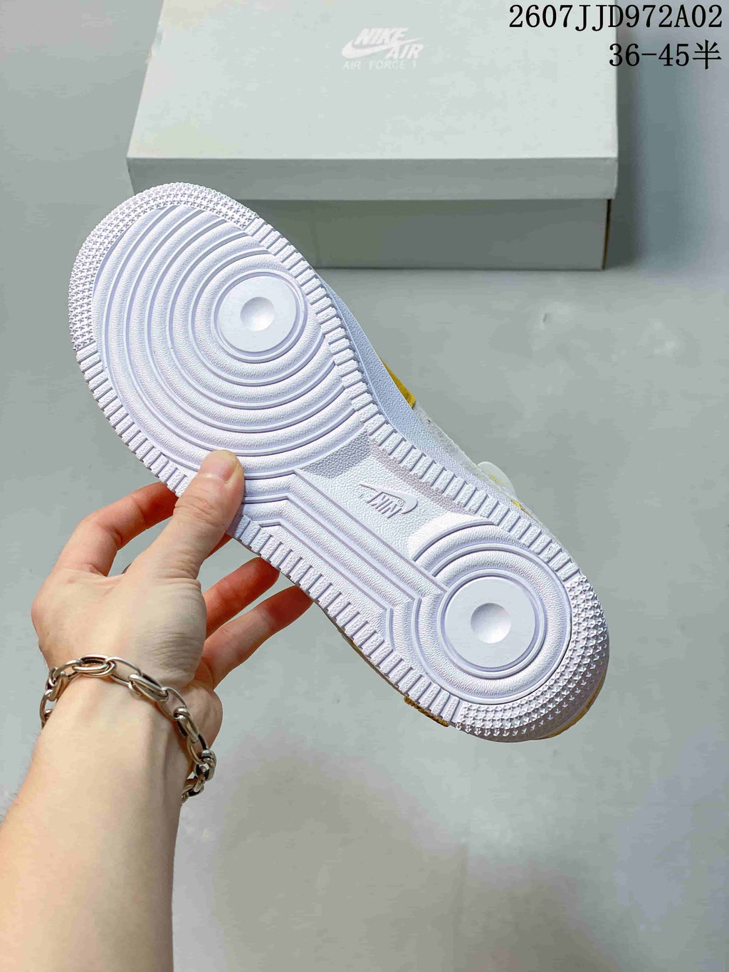 Underside of a white Nike Air Force 1 sneaker showing circular tread zones and ridged outsole pattern.