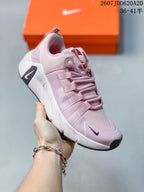 Three-quarter side view of the pink and white Nike training shoe showing the lace system, padded collar, Nike Swoosh, and sculpted sole.