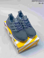 Pair of dark gray Adidas Ultraboost Light sneakers displayed on a yellow and white shoebox.