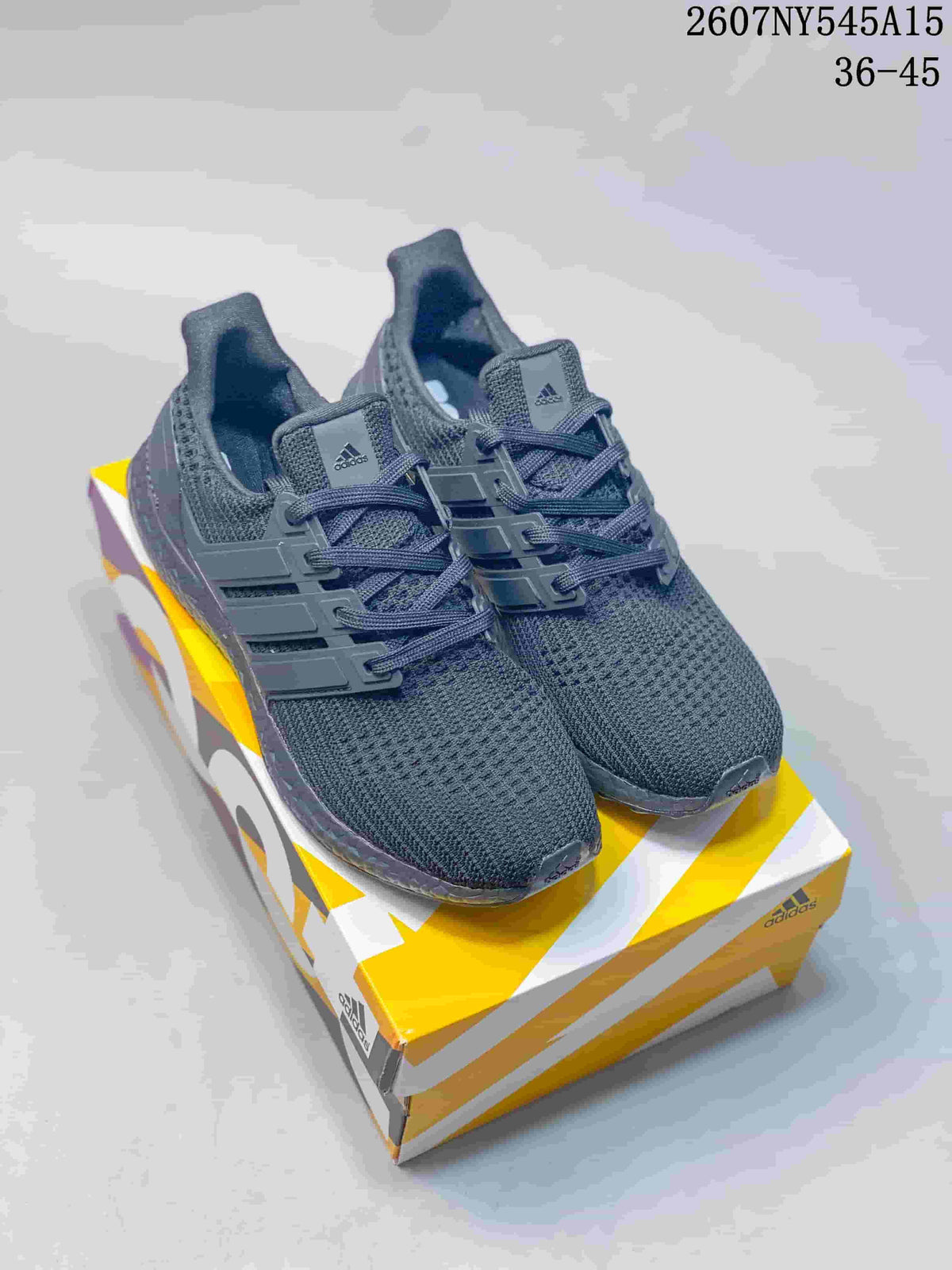 Pair of dark gray Adidas Ultraboost Light sneakers displayed on a yellow and white shoebox.