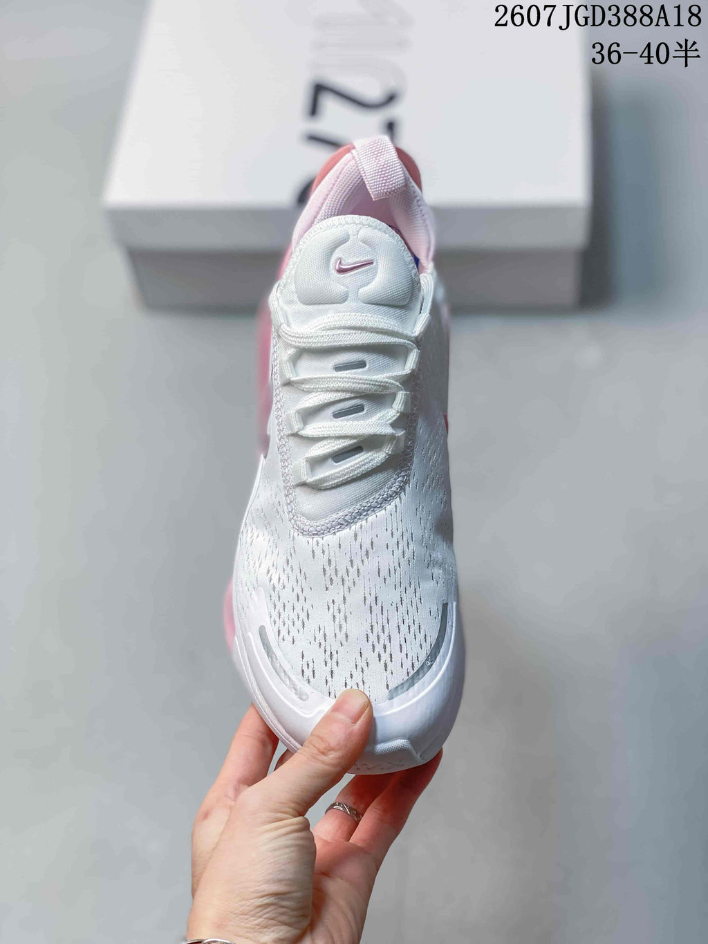 Front view of the sneaker showing the white upper, lace system, padded tongue, and pink accents.