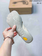 Close view of the textured outsole on an off-white five-finger shoe, with a Vibram badge at the heel.
