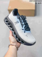 Angled side view of a white and black On Cloudtilt sneaker with a dark segmented outsole.