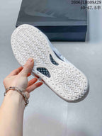 Underside of a white sneaker showing a patterned outsole and cutout sections.