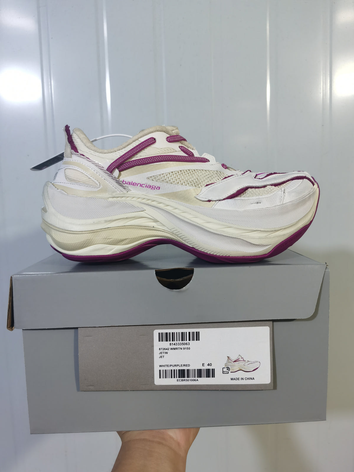 Side profile of the white and purple Balenciaga Jett sneaker resting on its shoebox, with the product label visible.