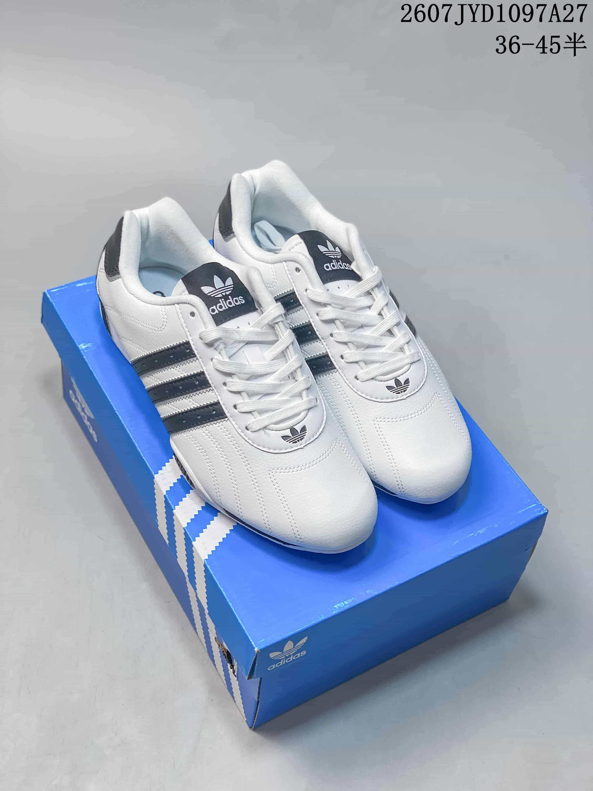 Pair of white and black Adidas Superstar sneakers displayed on a blue shoebox.