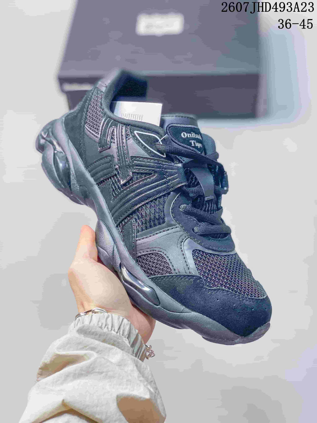 Angled view of the dark Onitsuka Tiger TIGRUN sneaker showing its retro running-inspired shape and layered upper.