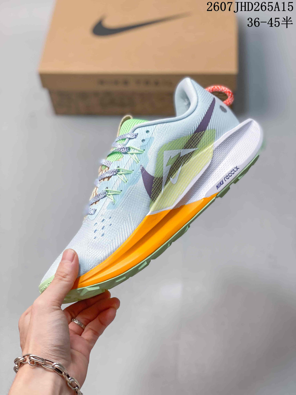 Side view of a Nike Pegasus Trail 5 sneaker showing the layered upper, Nike branding and contrasting orange midsole section.