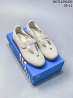 Off-white Adidas Originals Samba Jane sneakers displayed on a blue shoebox with cream interiors and brown-toned outsoles.