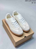 Pair of white and light grey DESCENTE low-top sneakers displayed on a shoebox, with a gum-colored outsole.