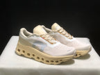 Three-quarter front view of the light-colored On Cloudmonster 1 sneakers.