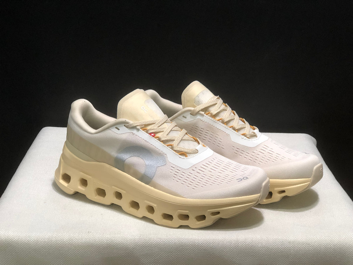 Three-quarter front view of the light-colored On Cloudmonster 1 sneakers.