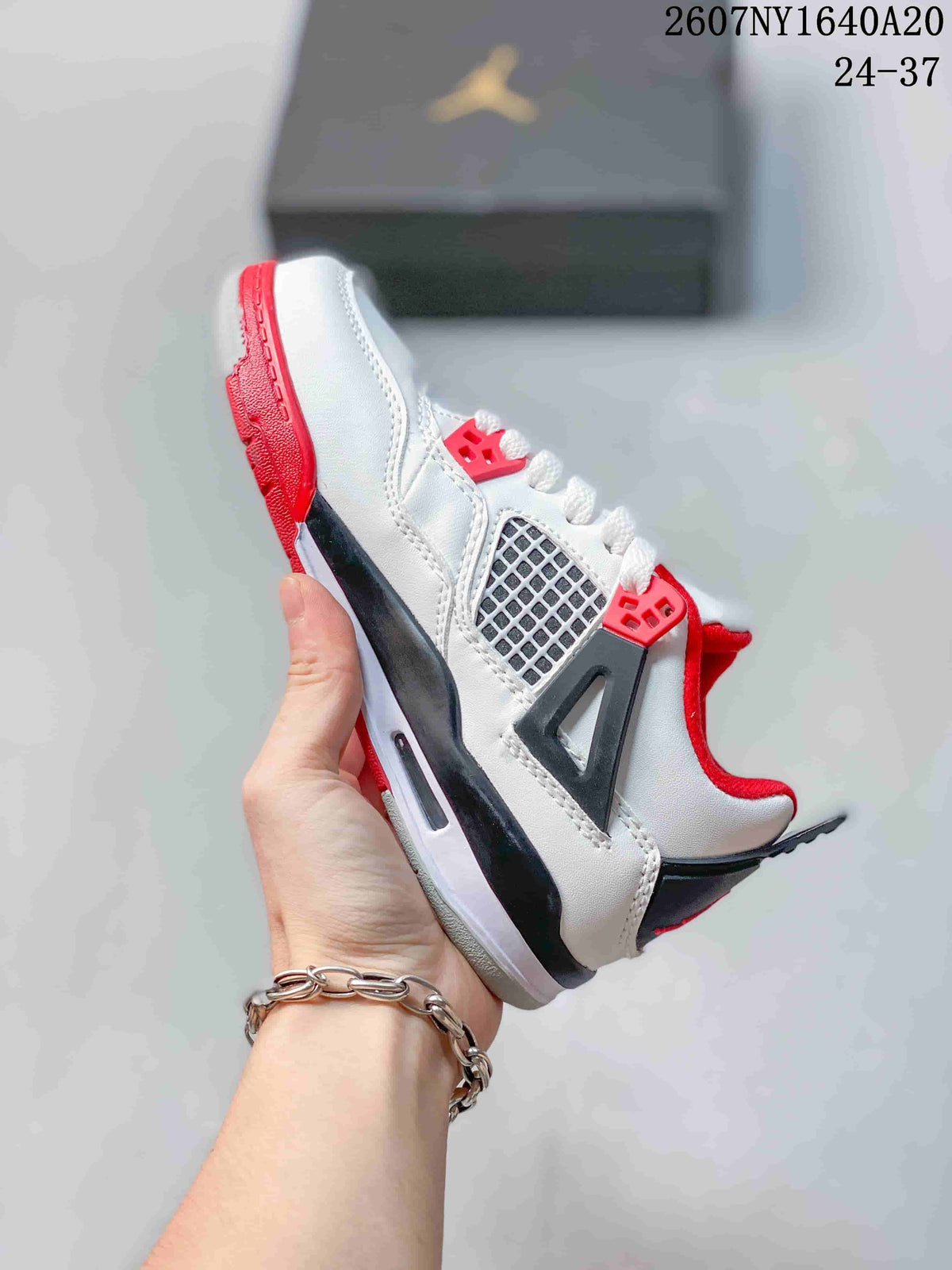 Side view showing the white upper, mesh panel, lace eyelets, black support detail, and red outsole.
