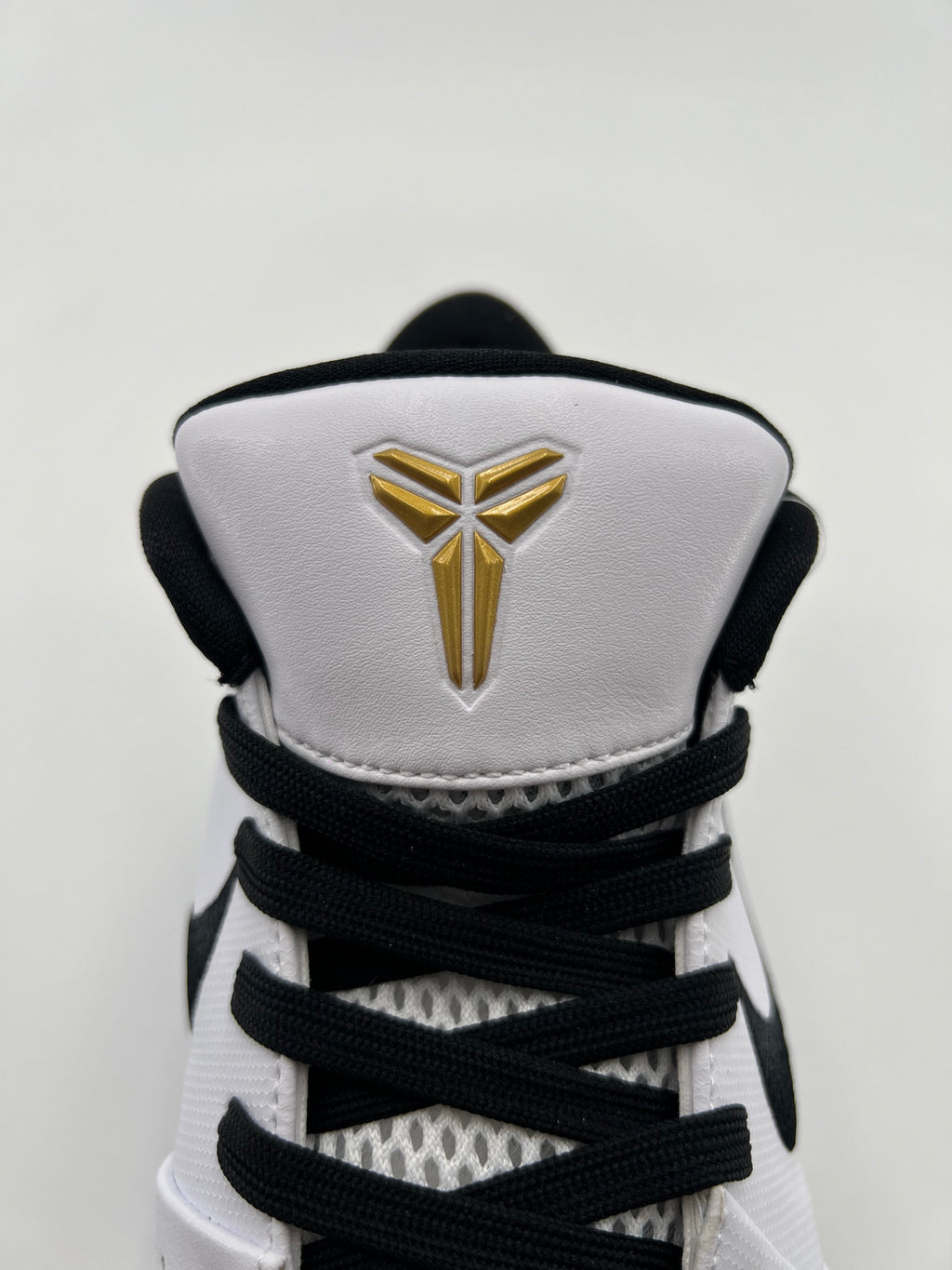 Front view of the tongue with gold Kobe emblem and black laces