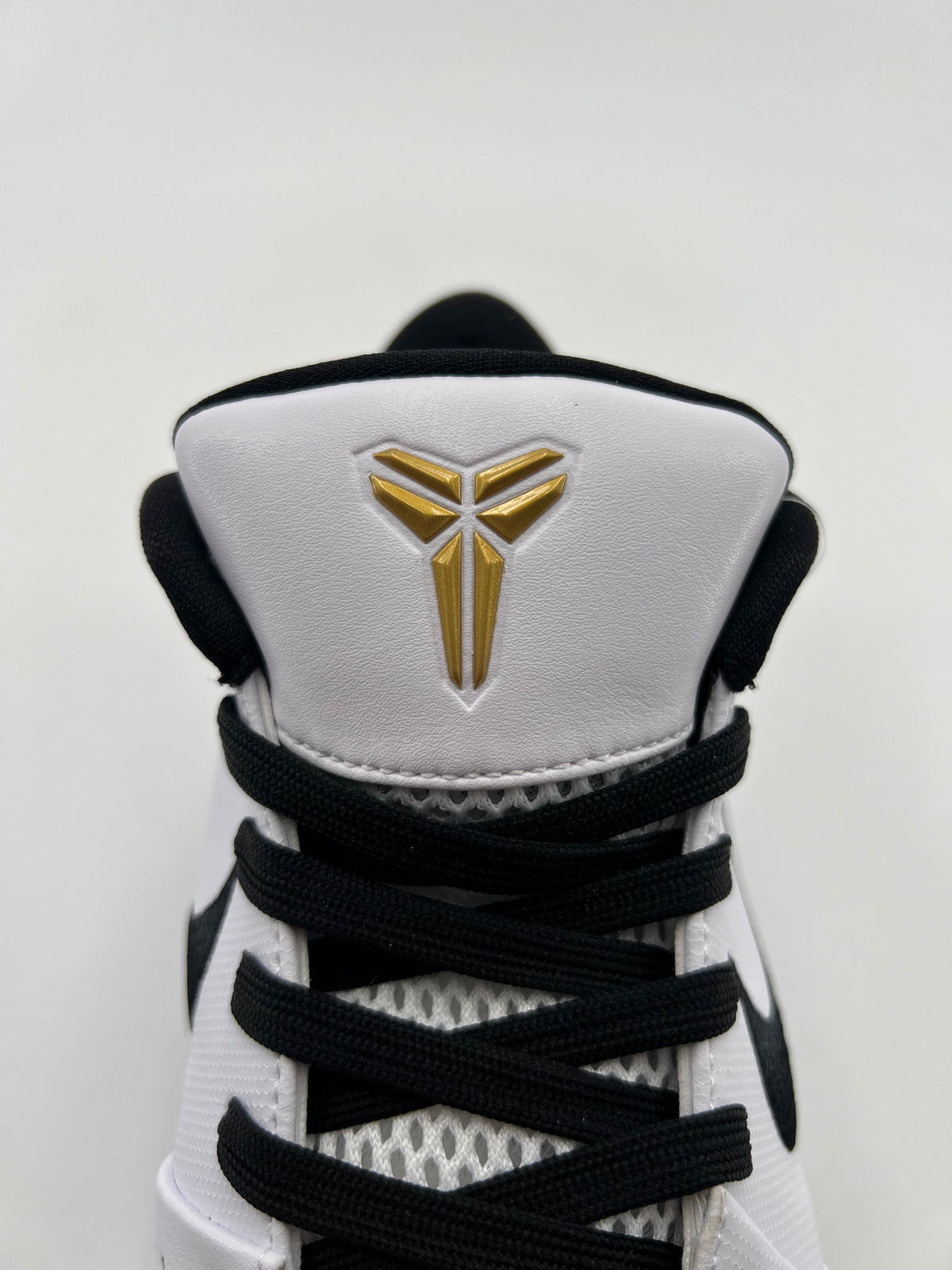 Front view of the tongue with gold Kobe emblem and black laces