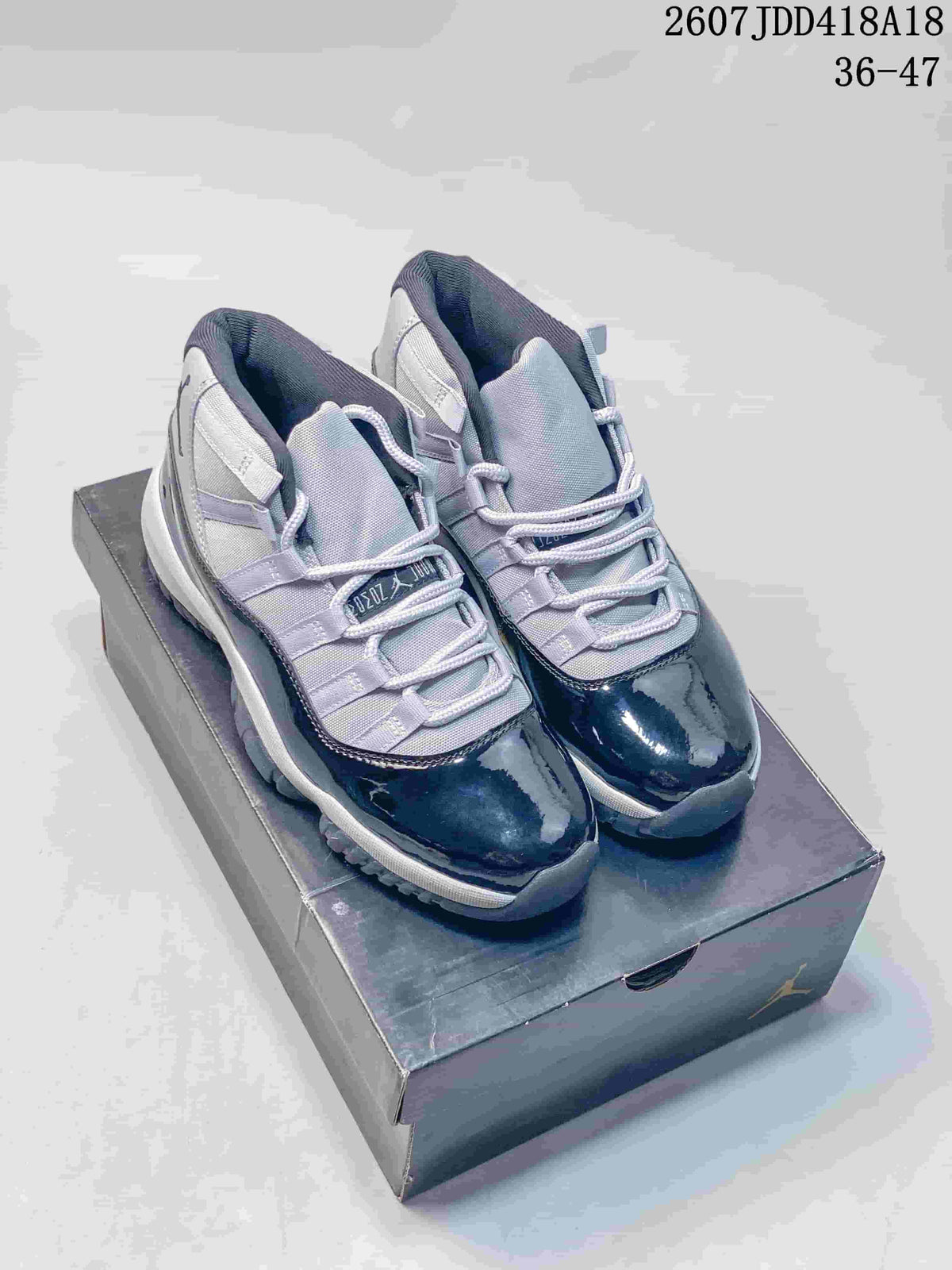 Pair of Jordan Air Jordan 11 high-top sneakers in dark navy, grey and white, displayed on a shoebox; overlay shows style code 2607JDD418A18 and size range 36–47.