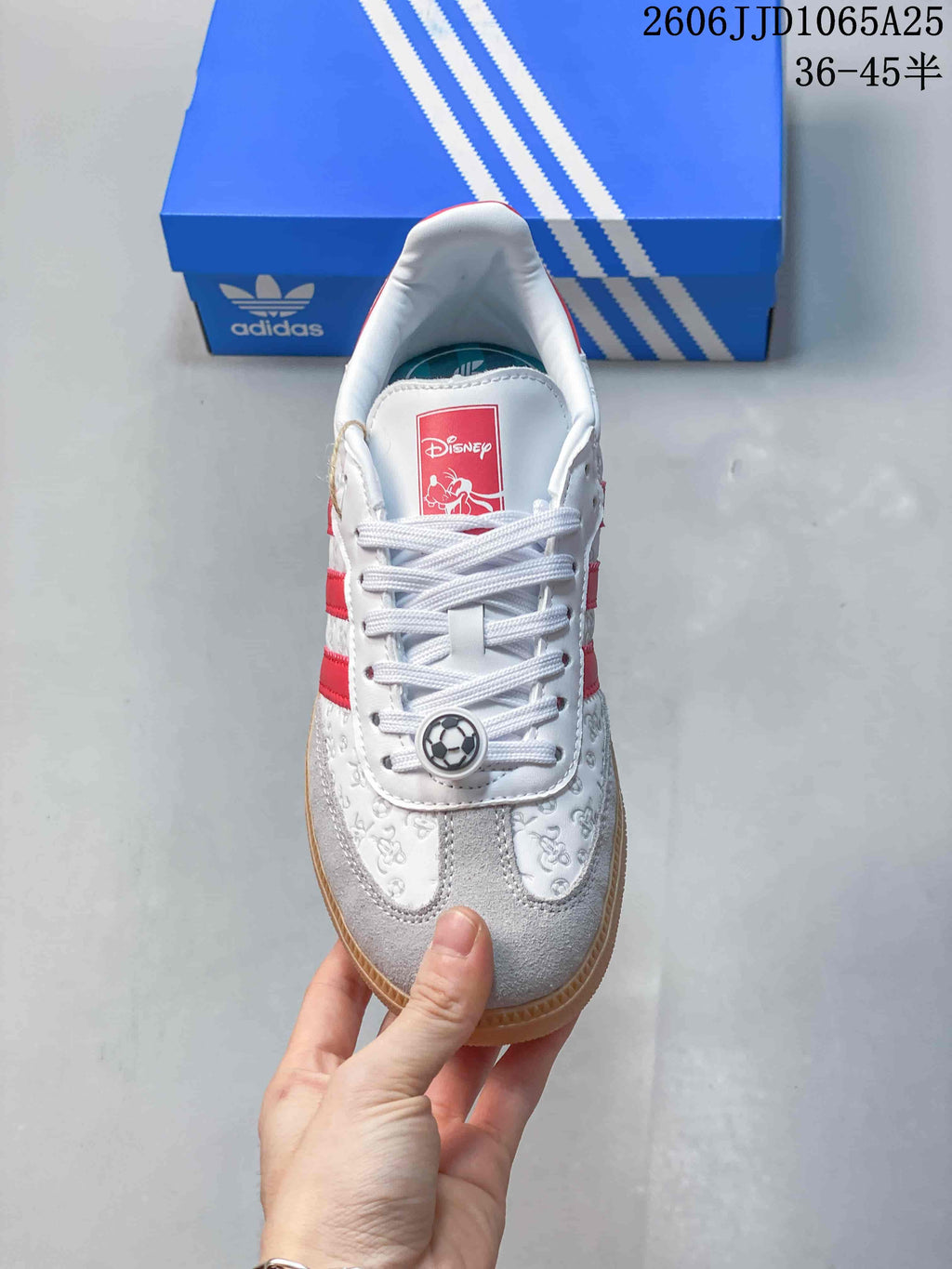 Top view showing white laces, a red Disney tongue label, embossed upper graphics, and a soccer-ball lace ornament.