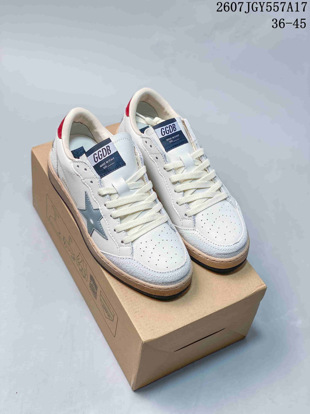 Pair of white Golden Goose Ball Star sneakers displayed on a shoebox, showing the star detail, red heel accents, and the visible 36–45 size range.