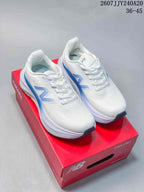 Pair of white and blue New Balance Fresh Foam X More v6 shoes displayed on a red shoebox.