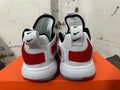 Rear view of white Nike sneakers showing red heel panels and layered white soles.