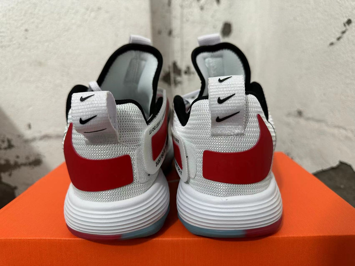 Rear view of white Nike sneakers showing red heel panels and layered white soles.