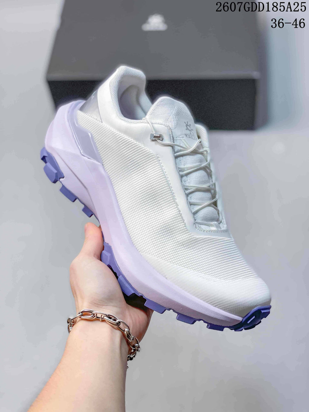 Three-quarter side view of the white and lilac KAILAS shoe showing its low-top profile, lace-up upper, and lugged outsole; overlay shows style code 2607GDD185A25 and size range 36–46.