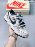 Close-up of a white sneaker with a navy Swoosh, red side label, graphic heel detail and perforated toe.