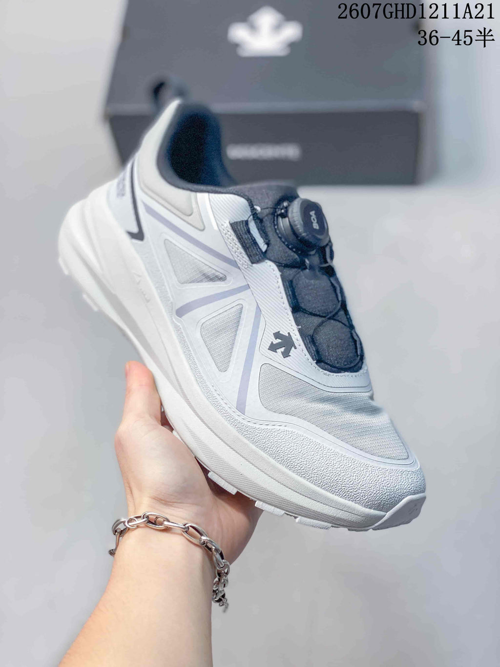 Side view of a light-colored DESCENTE sneaker showing the layered upper and lugged outsole.