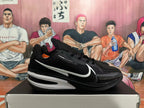 Side view of a black basketball shoe with white accents and a Swoosh-style mark