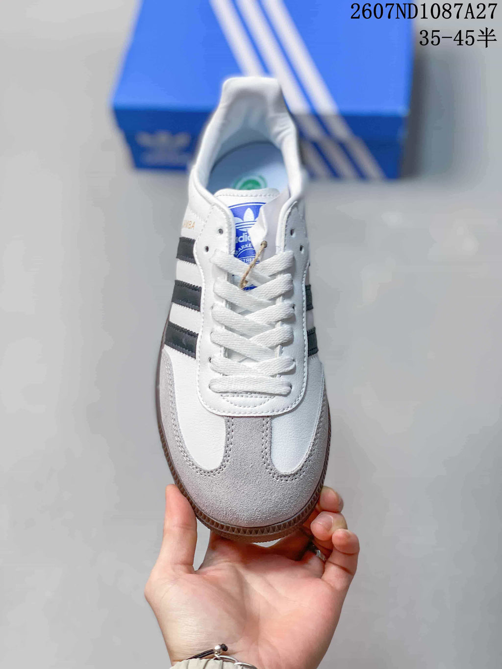 Top view showing white laces, gray toe panels, black stripes and blue adidas tongue branding.