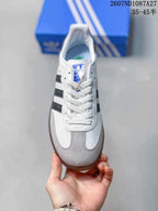 Top view showing white laces, gray toe panels, black stripes and blue adidas tongue branding.