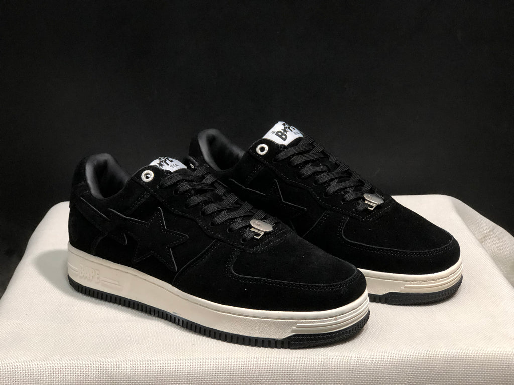 Three-quarter view of the black sneaker pair with tonal side stars and white midsoles.