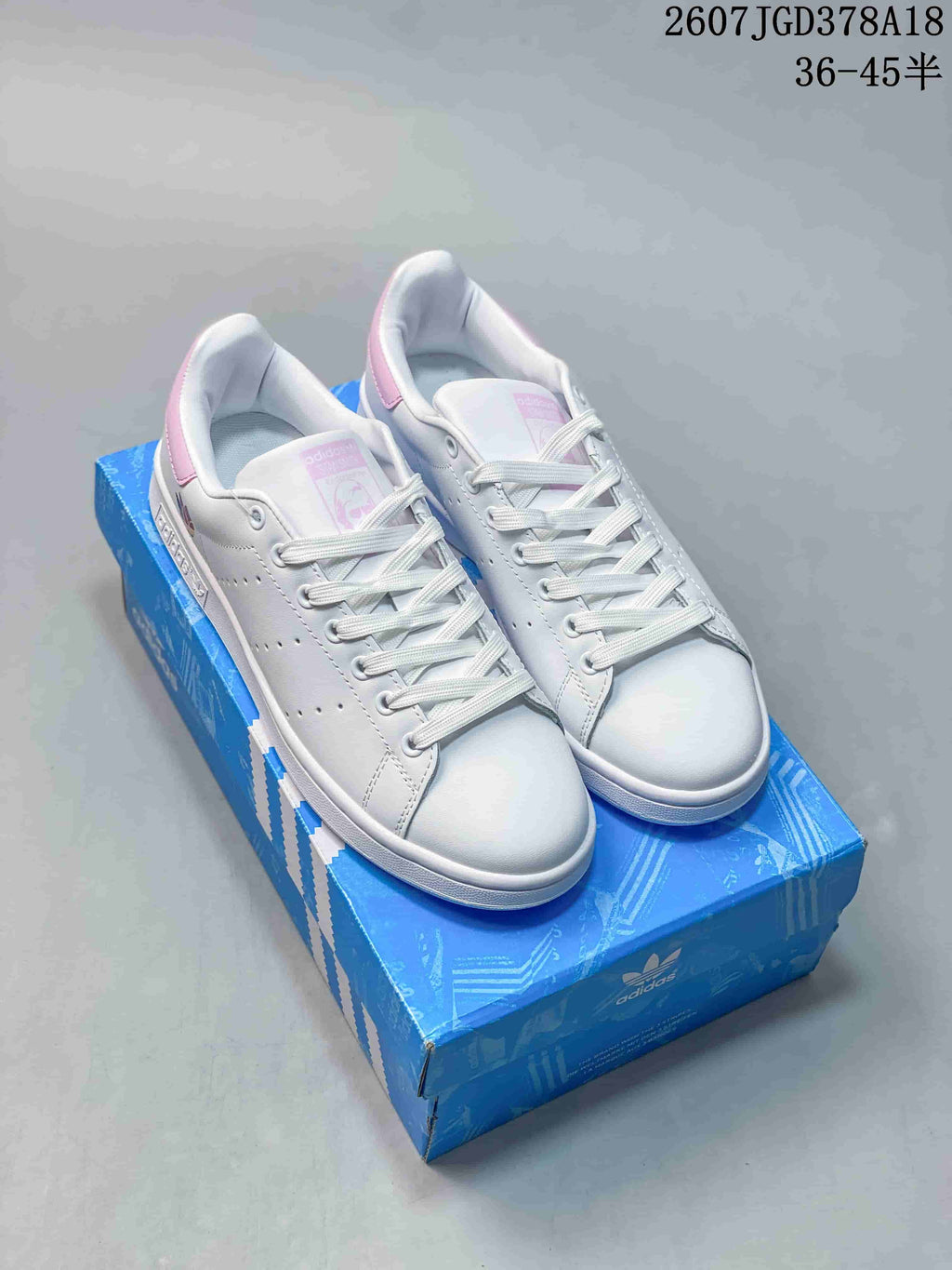 Pair of white and pink adidas Stan Smith sneakers displayed on a blue adidas shoebox; overlaid text shows style reference 2607TGD378A18 and a 36–45 half-size range.