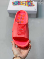 Top view of a coral Nike mule slide showing the open toe, textured upper panel and printed footbed.
