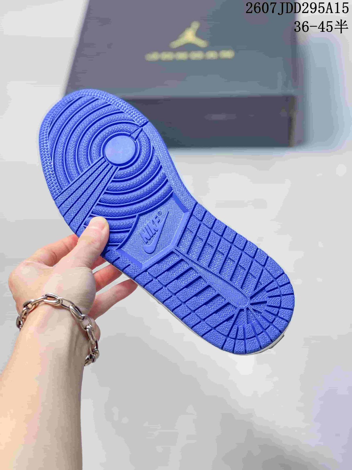 Blue rubber outsole of the sneaker showing a circular traction pattern and molded branding, with the shoe box in the background.
