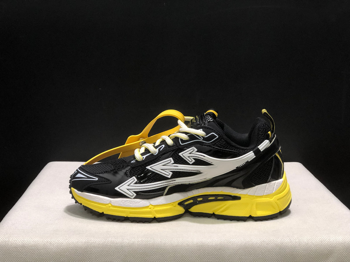Opposite side profile showing the black upper, white arrow graphics, yellow sole, and attached hangtag.