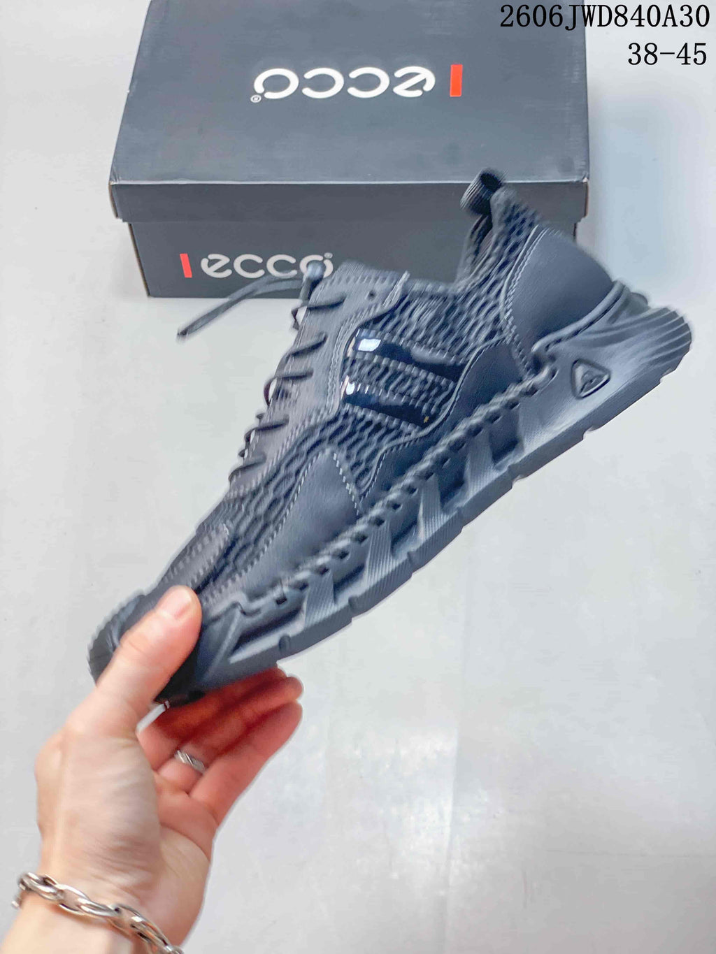 Side view of the charcoal sneaker with patterned mesh appearance and stitched overlays