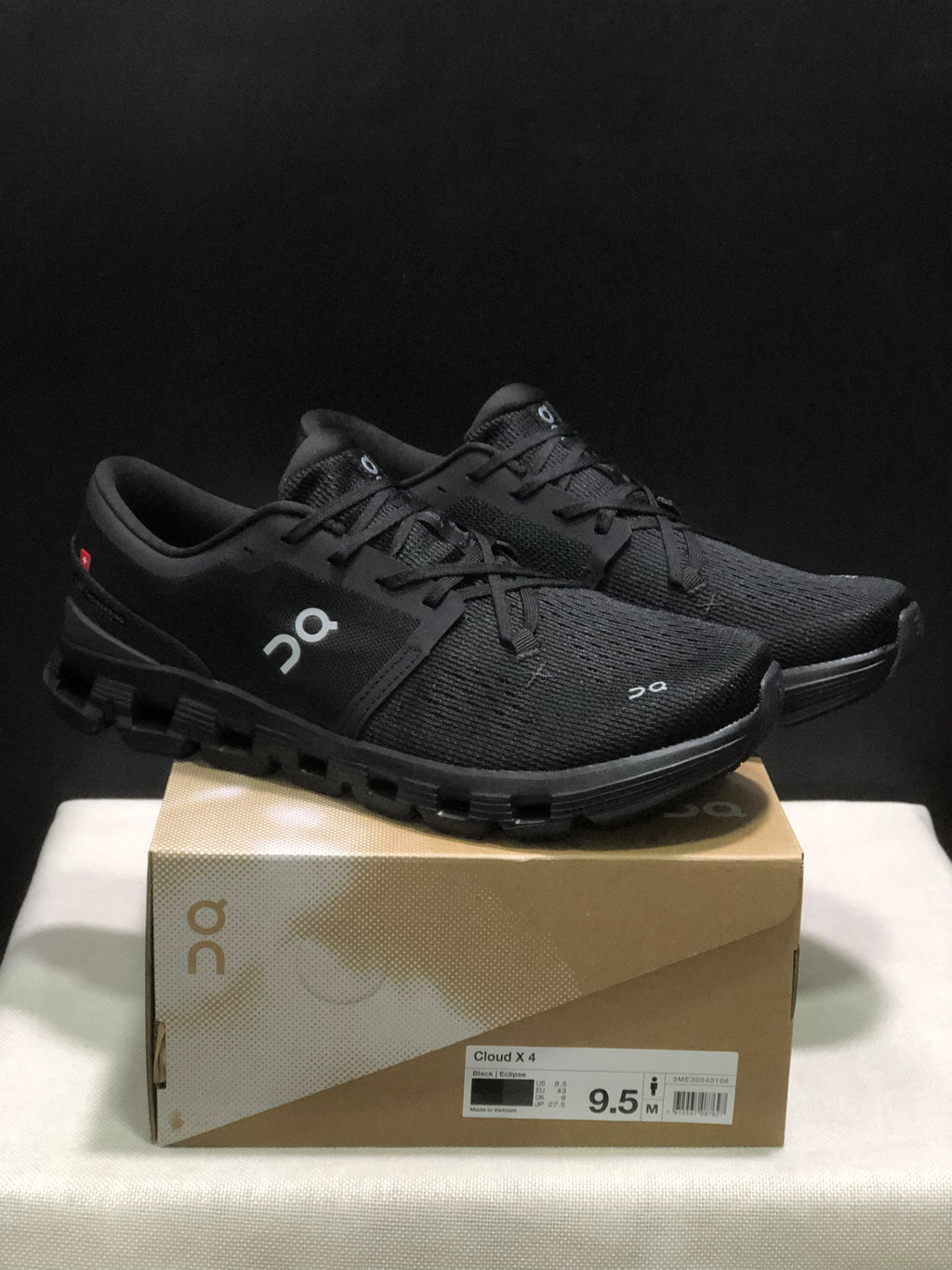 Black On Cloud X4 shoes displayed on a Cloud X4 box, with the box label visible.