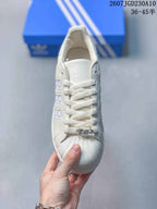 Top view of the sneaker showing the laces, tongue branding, shell toe, and decorative metallic bead detail.